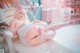 A woman in a pink and white outfit laying on a white chair.