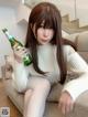 A woman sitting on a couch holding a bottle of beer.