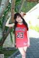 A woman in a red basketball jersey posing for a picture.