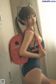 A woman in a bathing suit holding a red backpack.