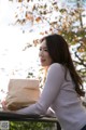 A woman sitting on a bench holding a brown paper bag.