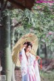 A woman in a pink and white kimono holding an umbrella.