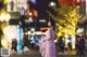 A woman in a pink dress standing in the middle of a city street.