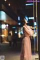 A woman in a pink dress standing in the middle of a street.