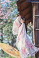 A woman in a pink and white kimono holding an umbrella.