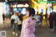 A woman in a pink dress standing in the middle of a street.