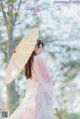 A woman in a pink kimono holding an umbrella.