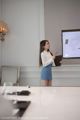 A woman standing in front of a projector screen holding a clipboard.