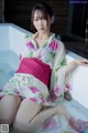 A woman in a kimono sitting in a bathtub.