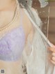 A woman wearing a purple bra and pearls standing in front of a mirror.