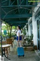 A woman with a blue suitcase standing in front of a building.