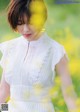 A woman in a white dress standing in a field of yellow flowers.