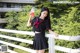 A woman in a school uniform holding a drink.