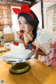 A woman in a red and white dress eating a strawberry cake.