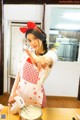 A woman in an apron holding a mixer in a kitchen.