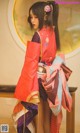 A woman in a red and purple kimono standing in front of a mirror.