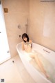 A naked woman sitting in a bathtub in a bathroom.