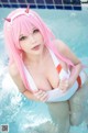 A woman with pink hair in a white bikini in a pool.