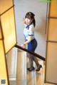 A woman in a blue skirt and a white shirt is standing on a stairwell.