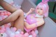 A woman in a pink bunny costume is sitting in a bathtub filled with balloons.