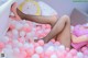 A woman in fishnet stockings and high heels laying in a ball pit.