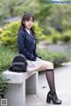 A woman in a school uniform sitting on a bench.