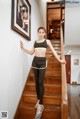 A woman in a black sports bra top and black leggings posing on a staircase.