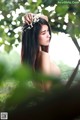 A woman with a flower crown on her head in the woods.