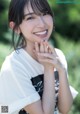 A young woman in a white shirt smiles at the camera.