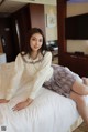 A woman sitting on a bed in a hotel room.