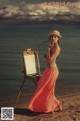 A woman standing next to an easel on a beach.