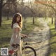 A woman in a white dress standing next to a bike.