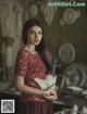 A woman in a red dress holding a white dove.