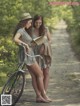 Two young women standing next to each other near a bike.