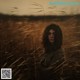 A woman standing in a field of tall grass.