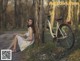 A woman sitting next to a tree next to an old bike.