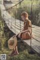 A young boy sitting on a wooden swing with a straw hat.