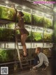 A man and a woman standing on a ladder in front of a fish tank.