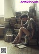 A woman sitting on the floor in front of a pile of books.