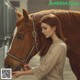 A woman standing next to a brown horse in a stable.