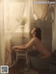 A naked woman sitting in a bathtub in a bathroom.