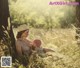 A woman holding a baby in a field of tall grass.