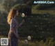 A woman standing in a field holding a dandelion.