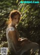 A woman in a white dress sitting in the grass.