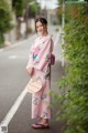 A woman in a pink kimono standing on the side of a road.