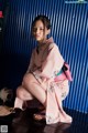 A woman in a pink kimono sitting on the floor.