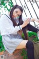 A woman in a school uniform sitting on a brick wall.