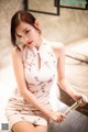 A woman in a white dress sitting on a marble bench.