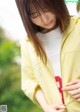 A woman in a yellow jacket is looking down at her phone.