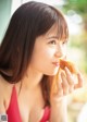 A woman in a red bikini eating a piece of bread.